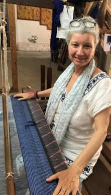 Carol Cassidy sitting at a weaving loom in Laos