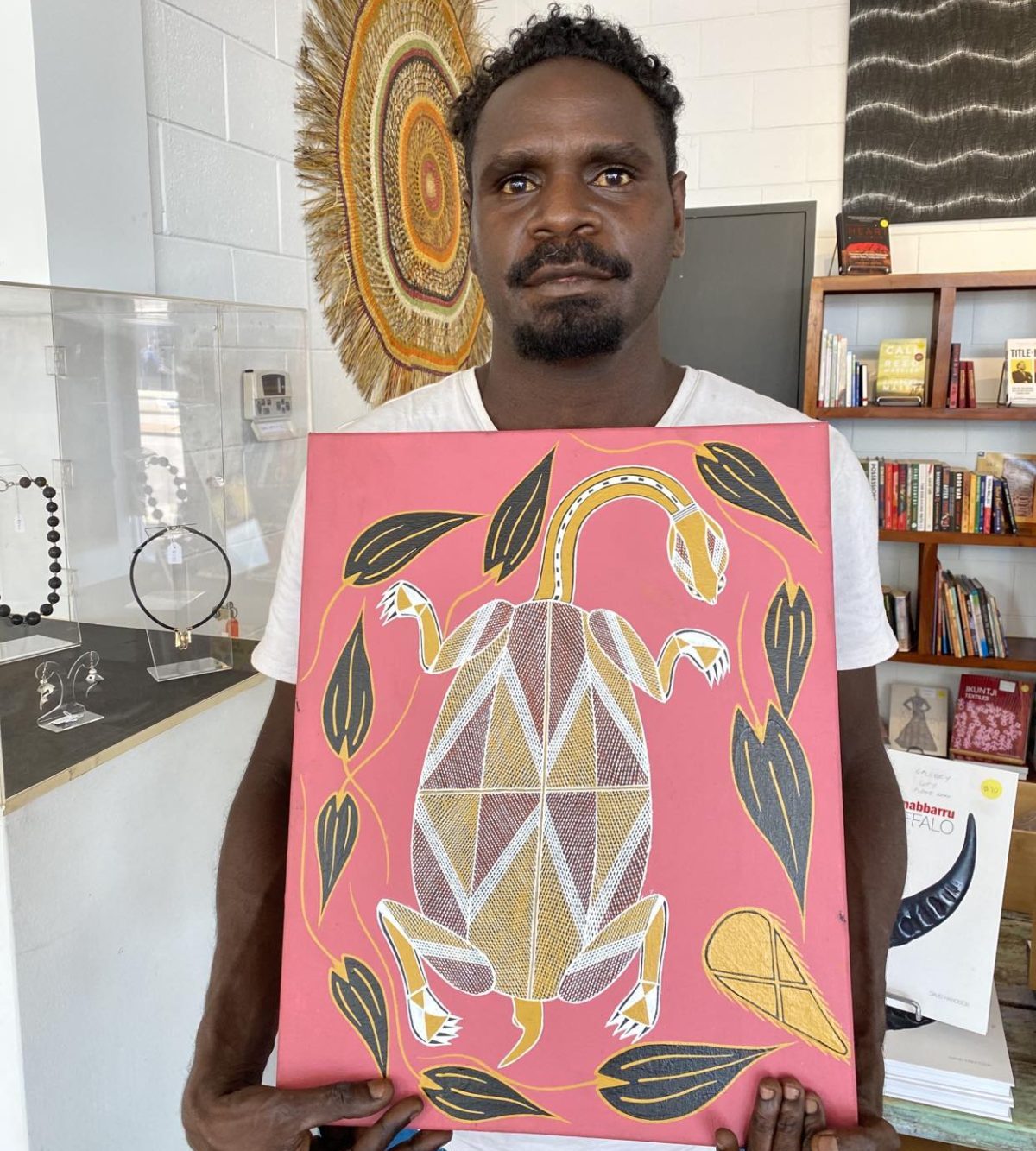 Austin Djorlom holding his painting of long neck turtle in Xray style Songlines Darwin Aboriginal art gallery