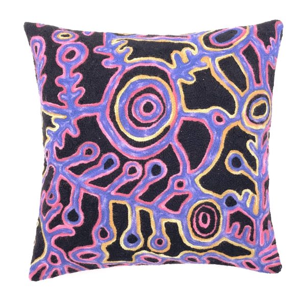 40 cm square cushion cover embroidered with wool in chainstitch designed by Theo Nangala Hudson. The colours are black, blue and tones of red with concentric circles and leaf like images